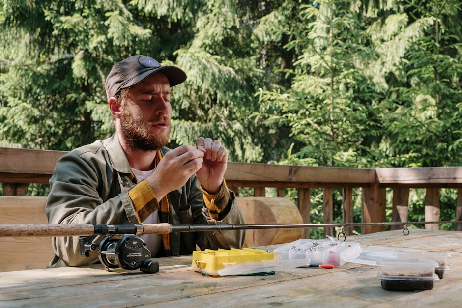 A man setting up fishing equipment on a wooden terrace surrounded by trees.