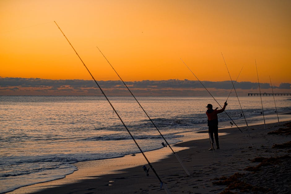 A lone fisherman casts his line at sunrise on a serene beach, capturing the peaceful morning.