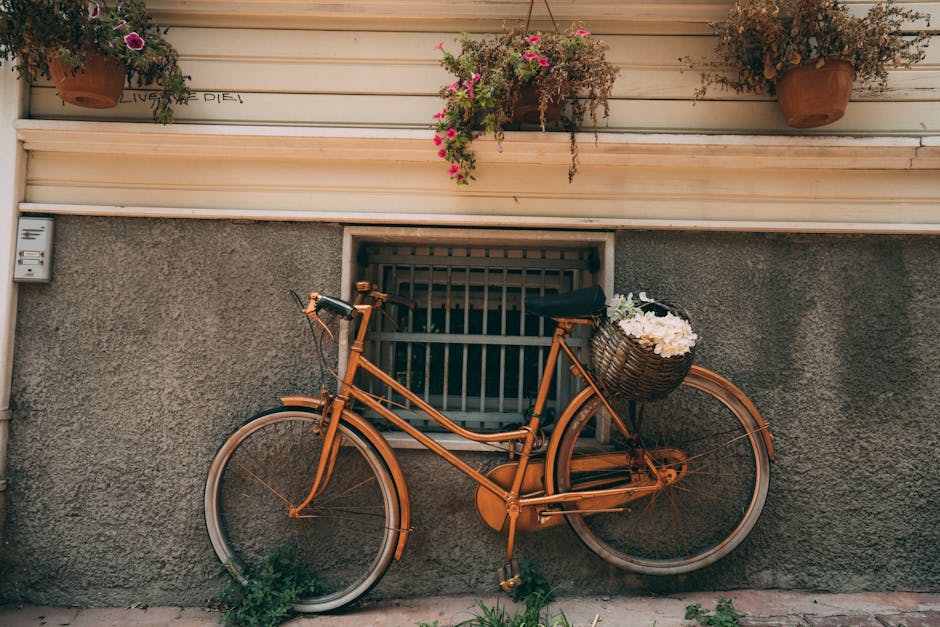 Charming vintage bicycle with a flower-filled basket leans against a rustic window, adorned with hanging pots.