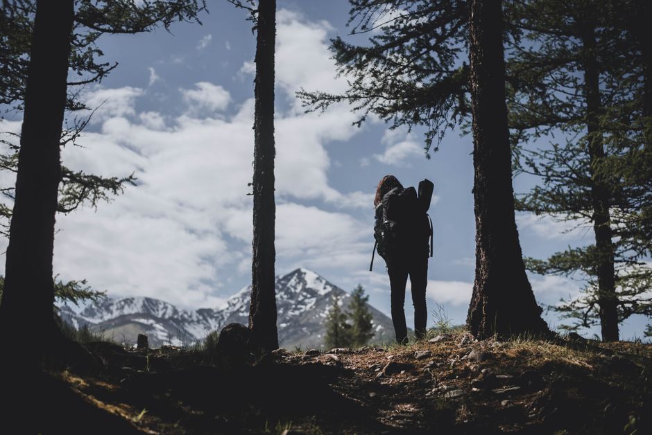 Silhouette of a hiker with backpack in Altai mountains, Russia, under blue skies.