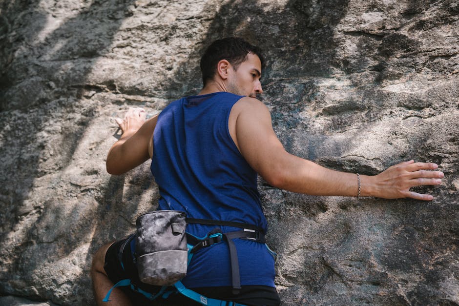 A man skillfully climbing a rocky cliff face during the day. Outdoor adventure and challenge.